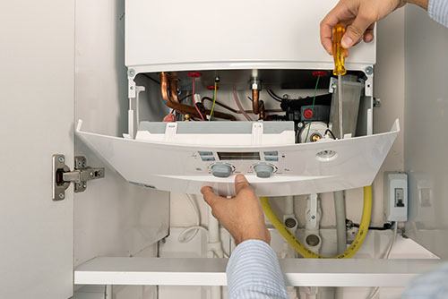 HVAC technician repairing an indoor boiler in North Salt Lake