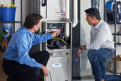 65df8c11f3e4c468cbd351a5_furnace repair vs replacement – Copy HVAC technician explaining furnace repair and maintenance to a homeowner in North Salt Lake, UT