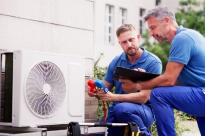 ac-installation-in-claremont-ca HVAC technicians reviewing an outdoor air conditioning unit in North Salt Lake, UT
