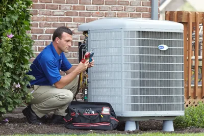 design-air-heating-and-air-conditioning-decatur-il-05 – Copy HVAC technician inspecting an outdoor air conditioning unit in North Salt Lake, UT